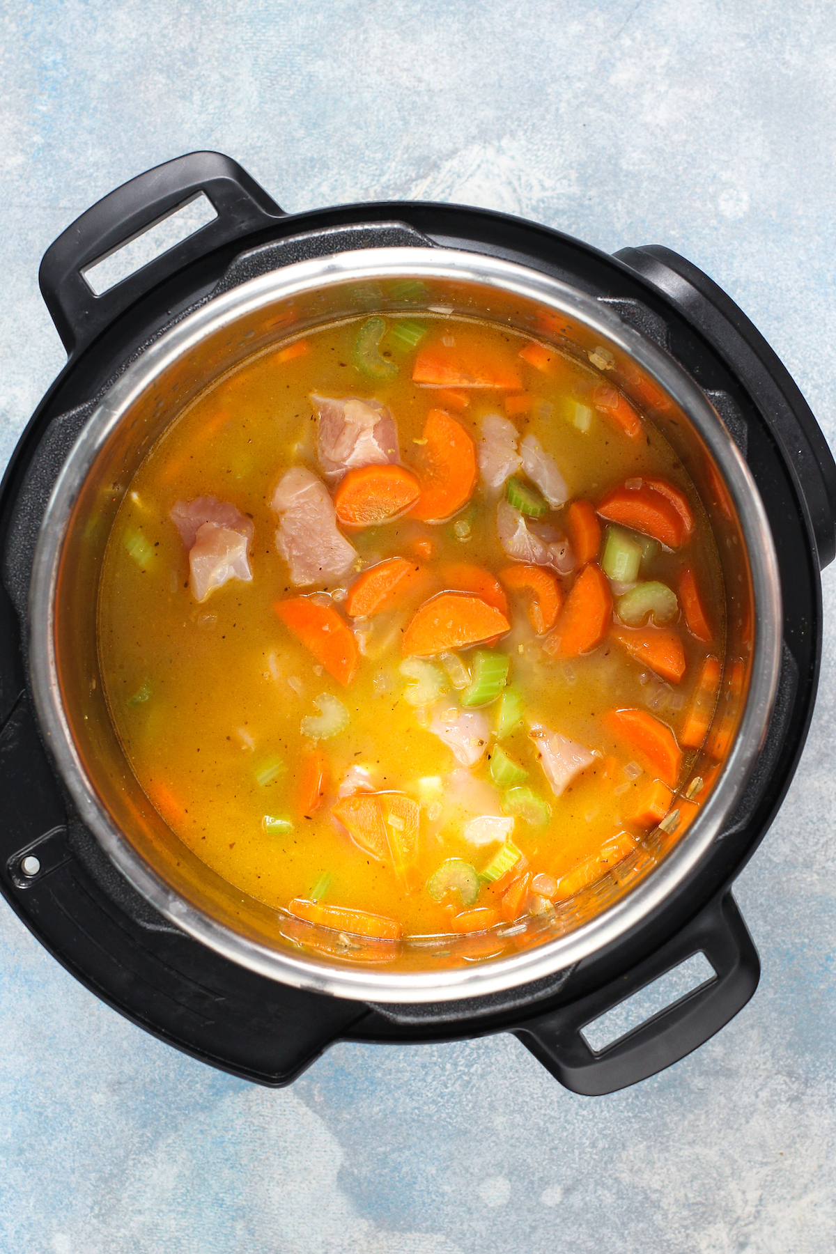 Chicken, broth, and veggies in an Instant Pot.