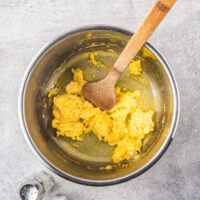 A wooden spoon scrambles eggs in the bowl of the Instant Pot after it's removed from the heat.