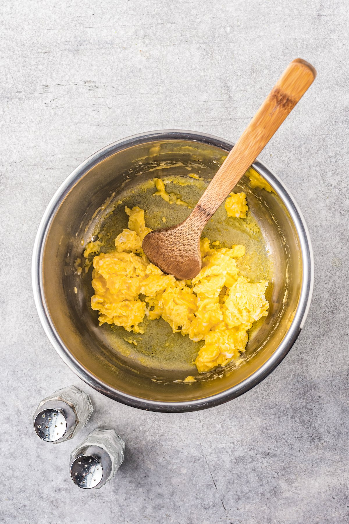 A wooden spoon scrambles eggs in the bowl of the Instant Pot after it's removed from the heat.