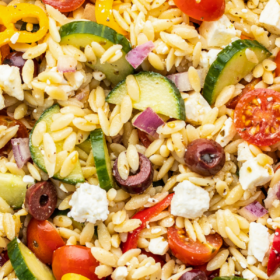 A bowl filled with greek pasta salad with feta.