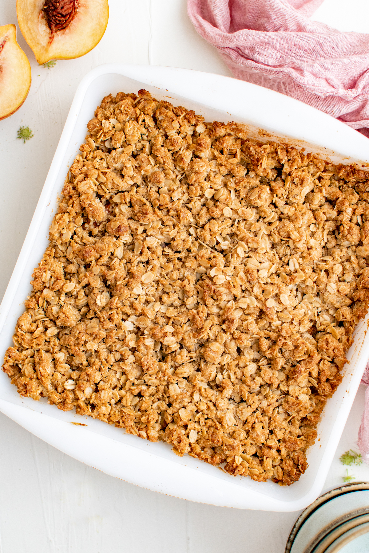 A square white baking dish with a baked oat topping visible from above.