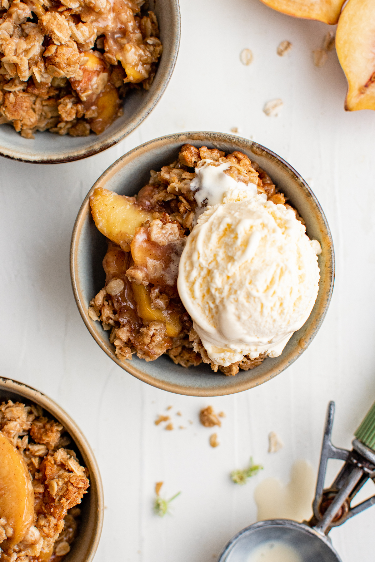 Peaches and oat topping with a scoop of ice cream on top, in a small bowl.