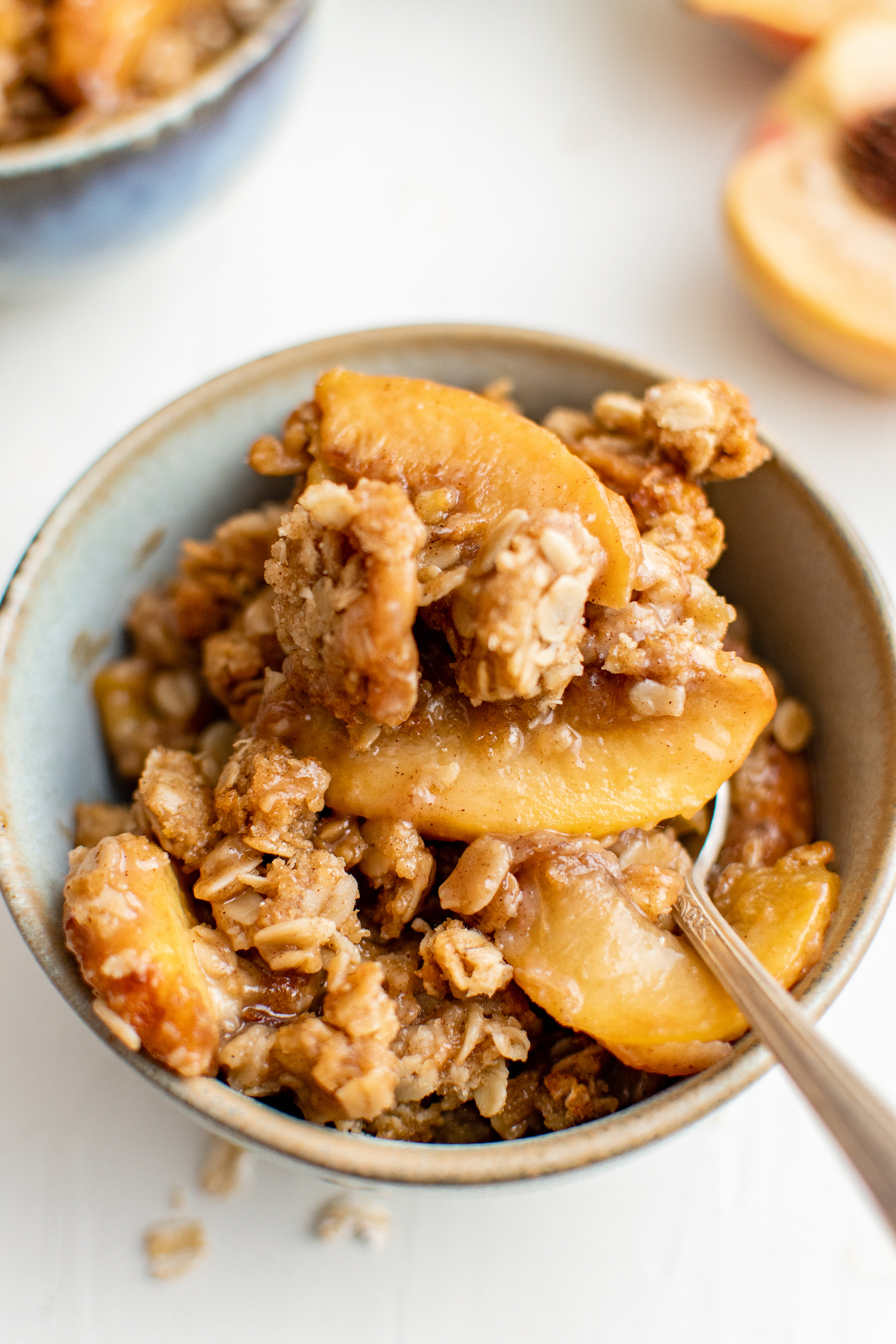 Close-up shot of peach crisp, with a spoon in the bowl.
