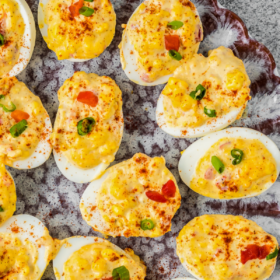 Deviled eggs with smoked paprika, pimentos and green onions on top.