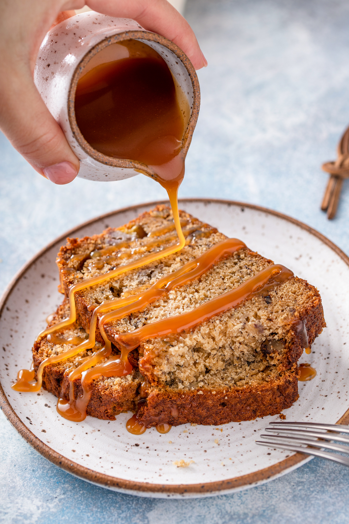 Caramel sauce being drizzled over slices of sweet quick bread.