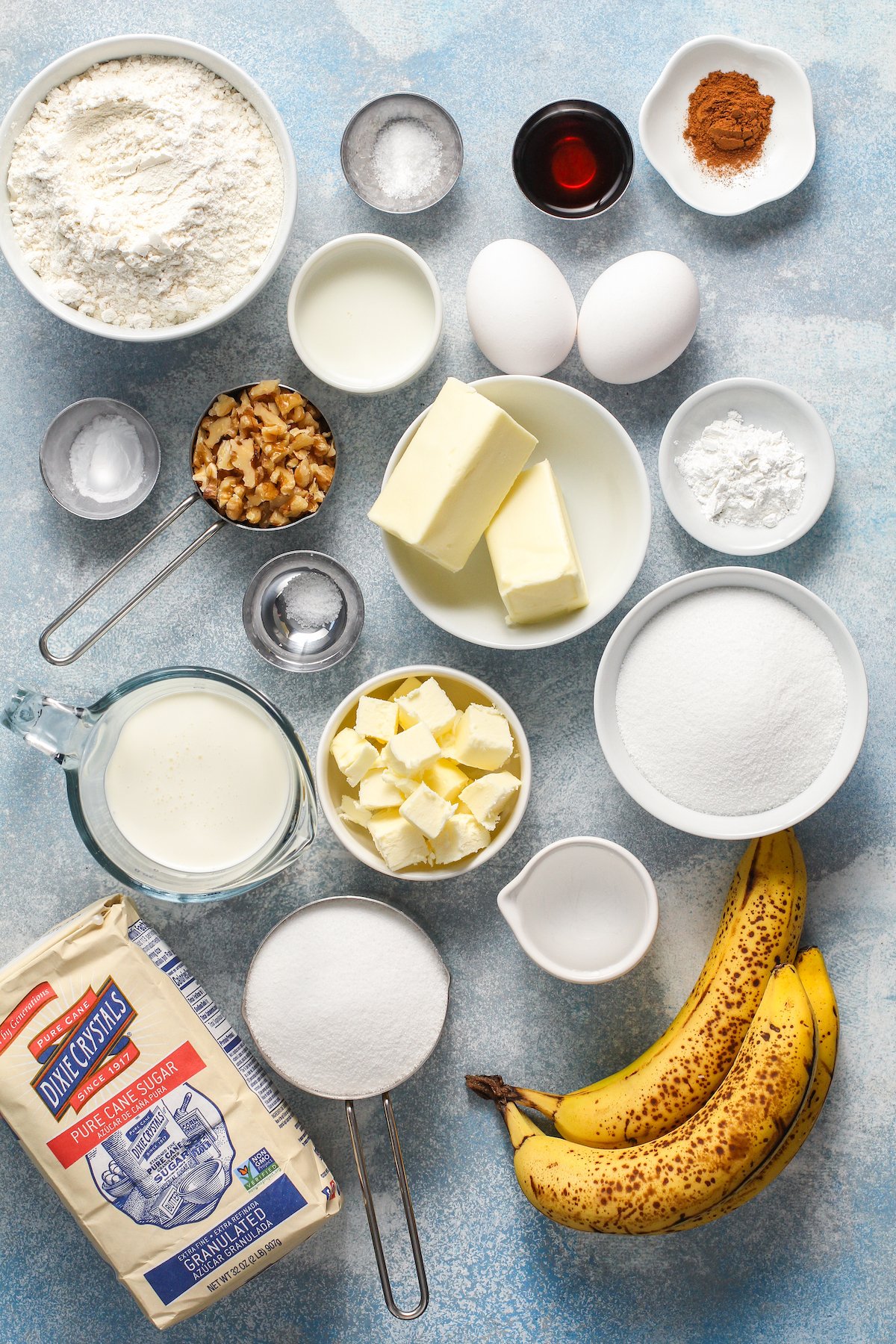 From top left: Flour, baking soda, vanilla, cinnamon, salt, walnuts, butter, baking powder, heavy cream, granulated sugar, water, bananas.
