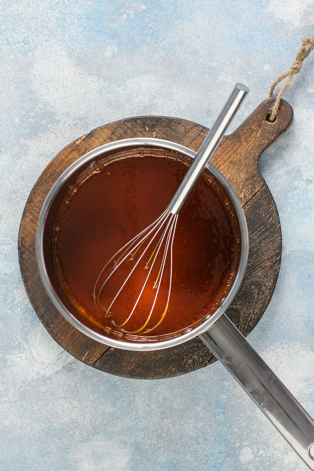 Finished caramel sauce in a saucepan with a whisk.