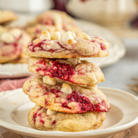 Four fruit and white chocolate cookies stacked on a small plate.