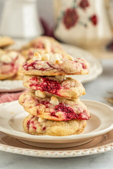 Four fruit and white chocolate cookies stacked on a small plate.