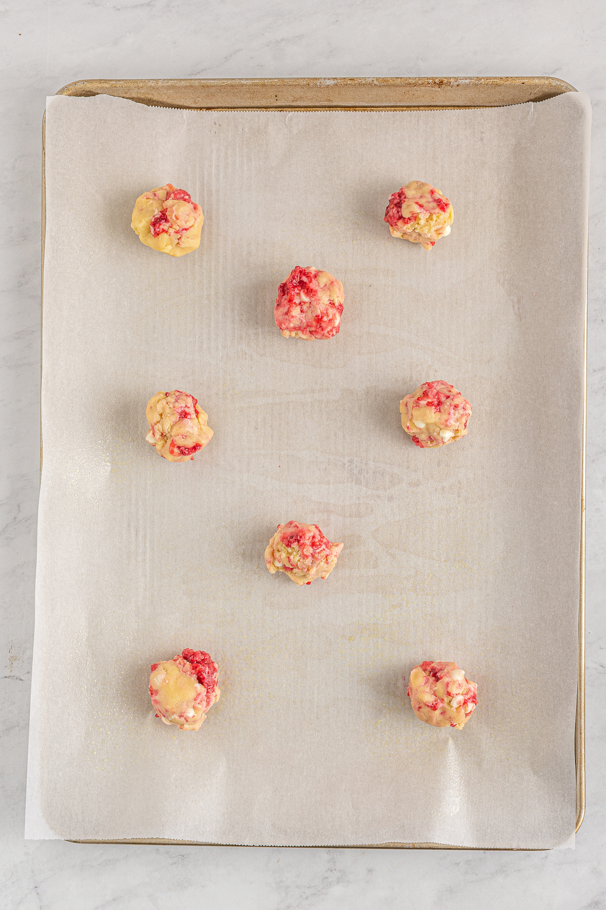 Cookie dough balls on a parchment-lined cookie sheet.