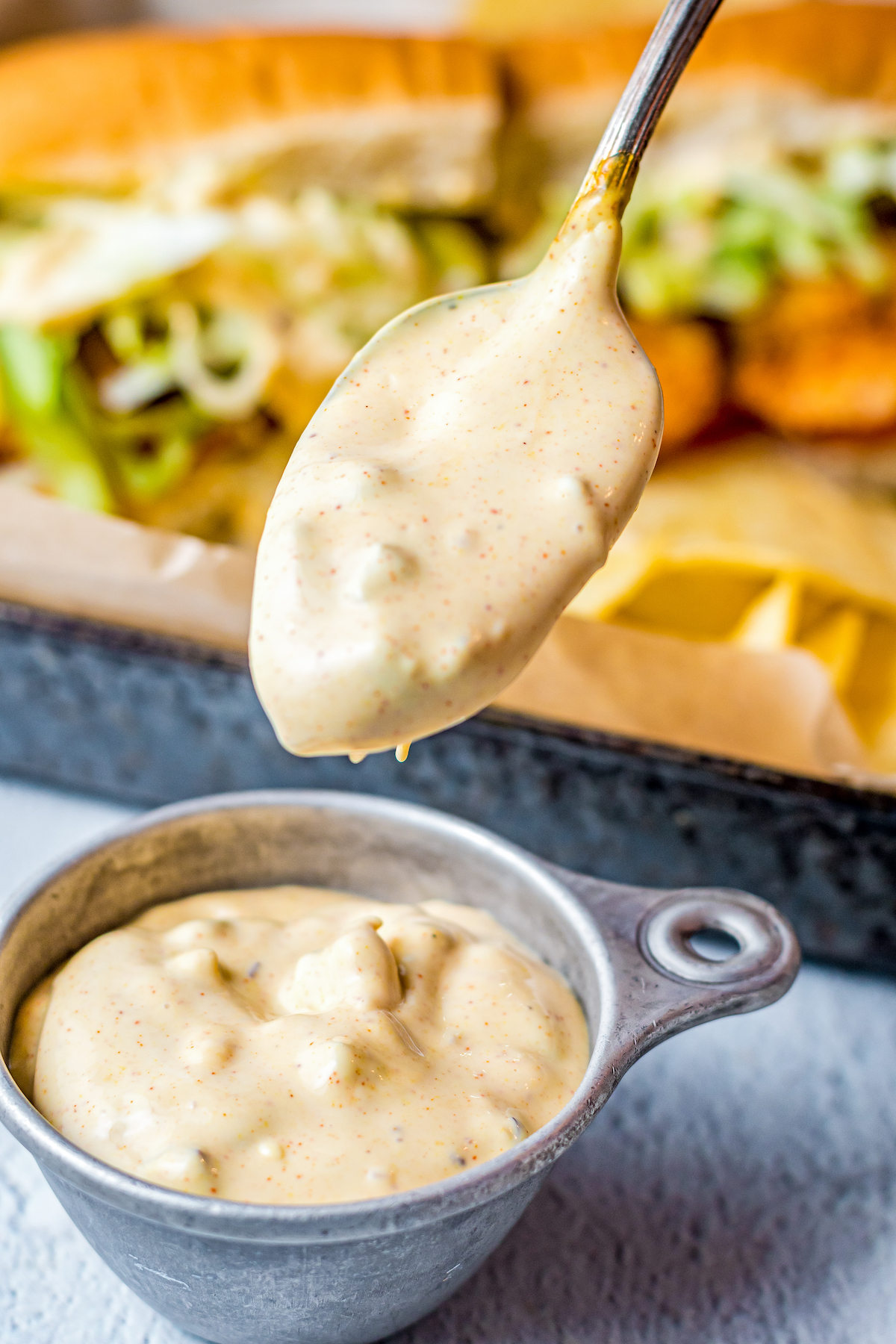 Remoulade sauce in a small dish. A spoon is lifting some of the sauce toward the camera.