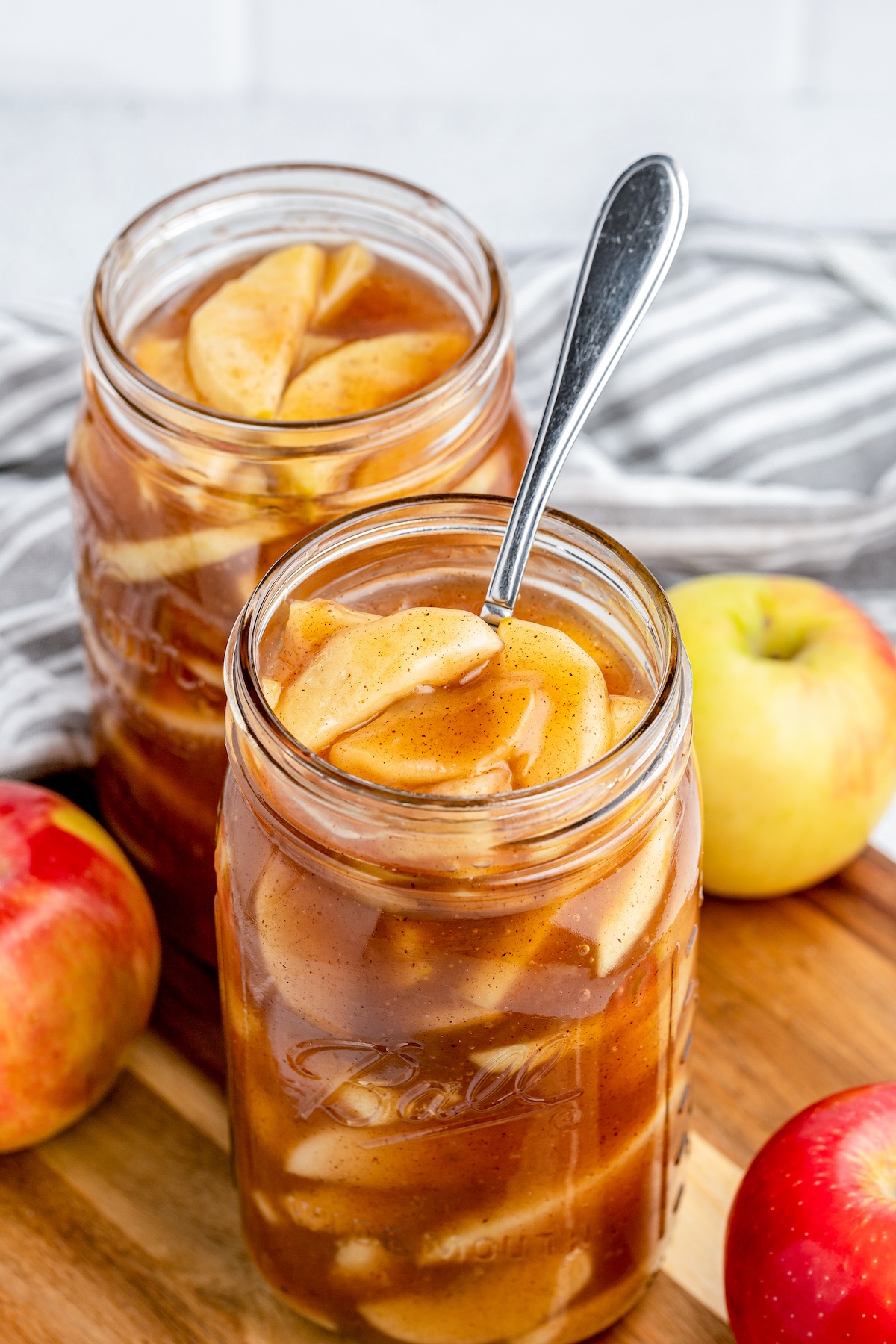 An open mason jar filled with apple pie filling, with a spoon.
