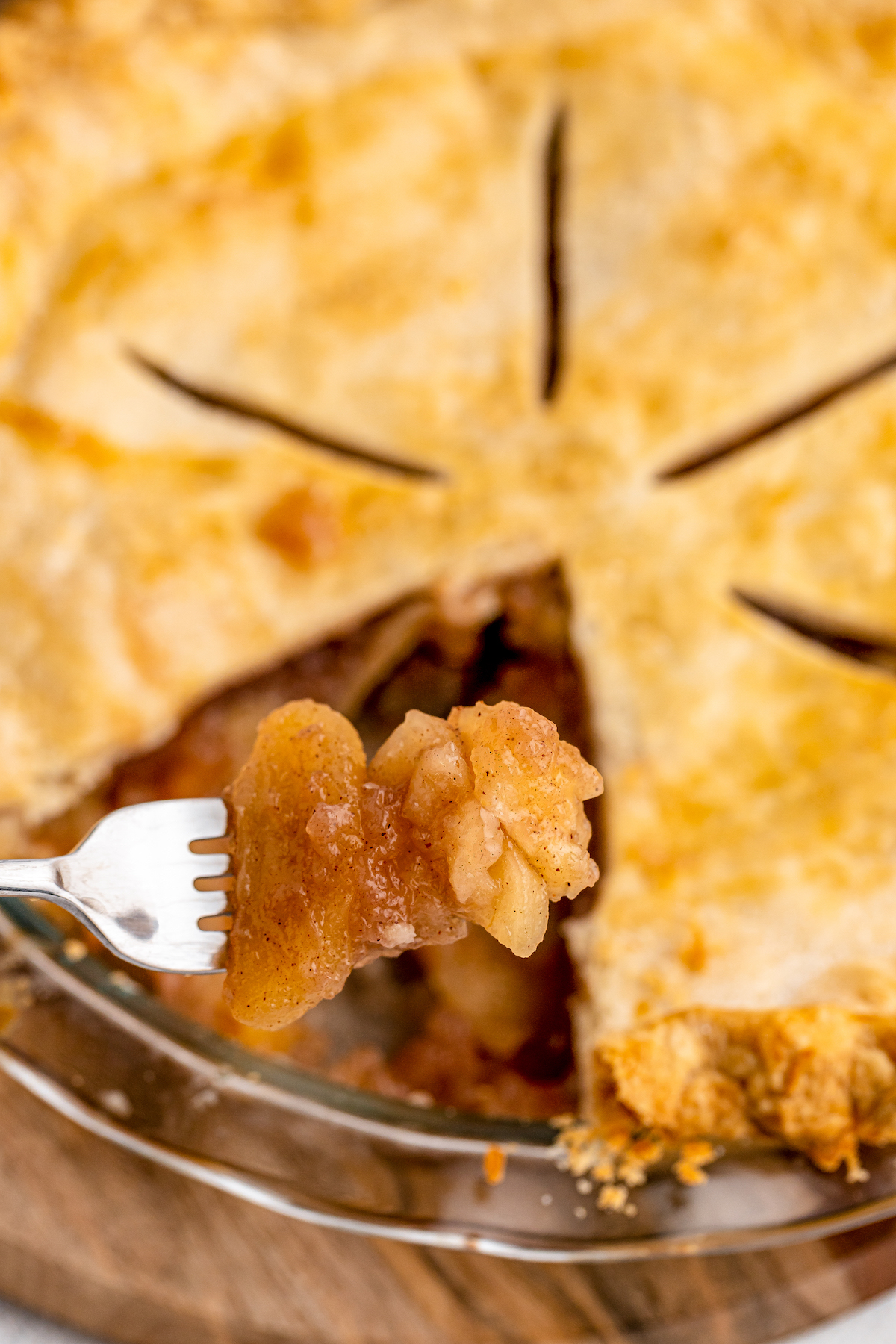 An apple pie in a pie tin with a slice missing.
