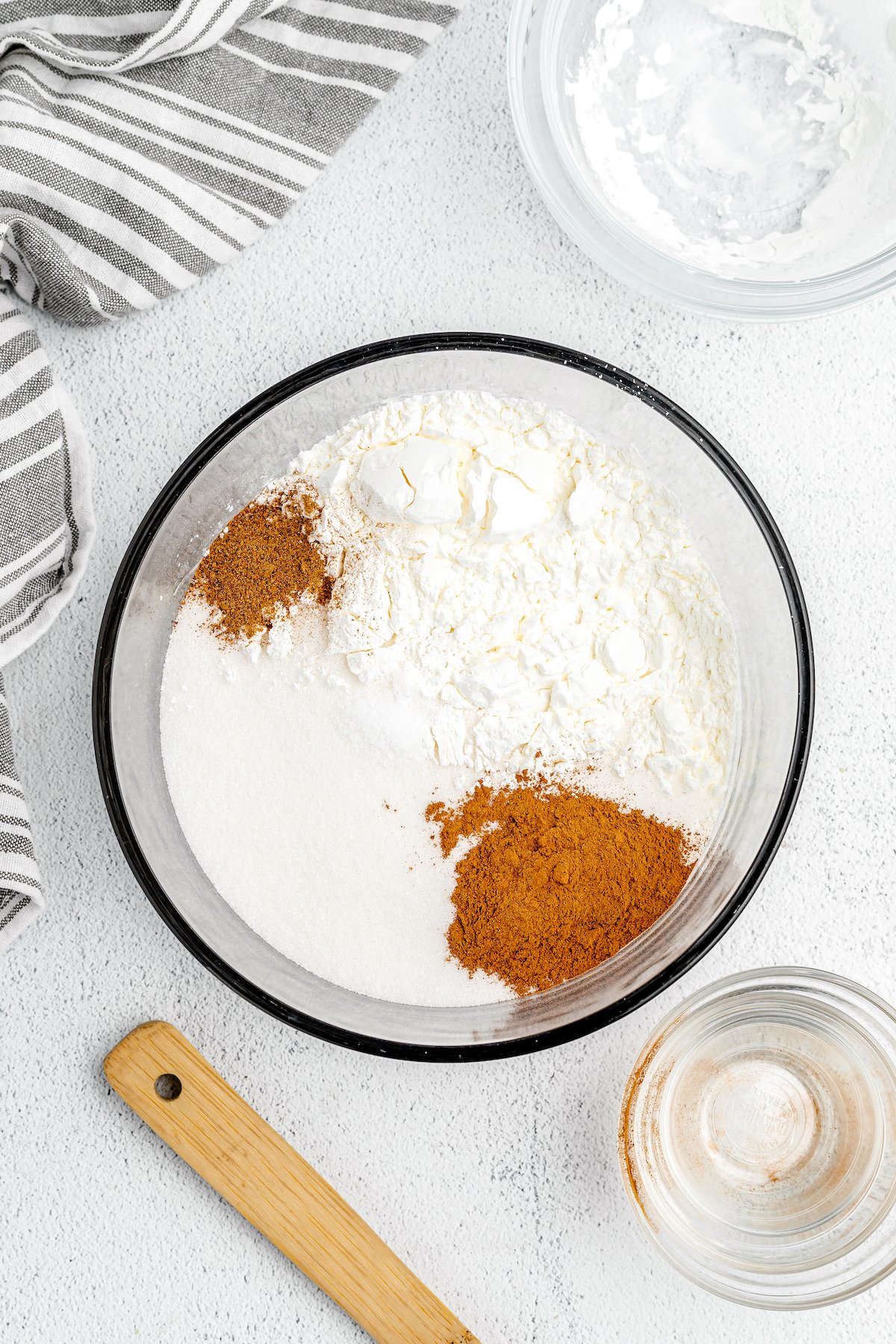Spices are added to cornstarch in a glass mixing bowl.