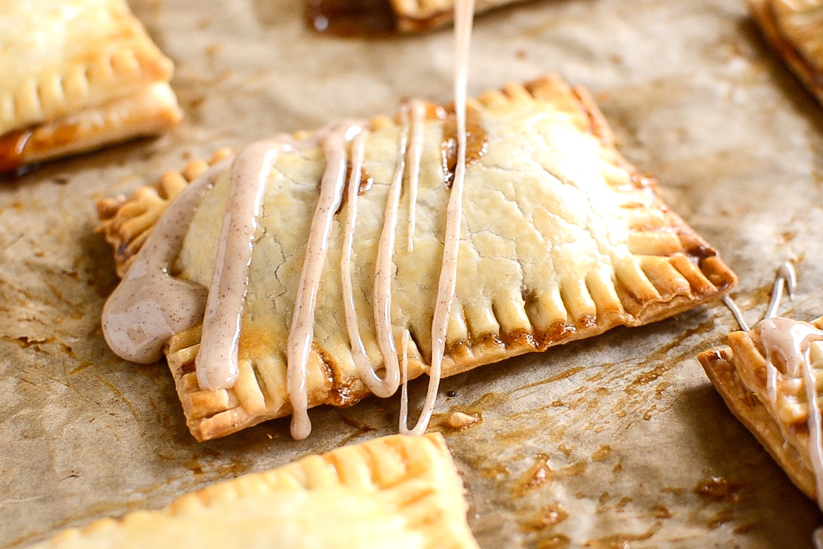 Baked poptart being drizzled with cinnamon icing.