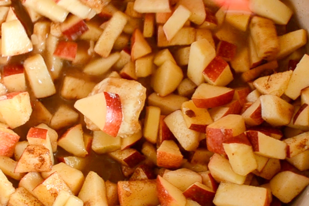 Chopped apples in a pot with brown sugar, cinnamon and more.