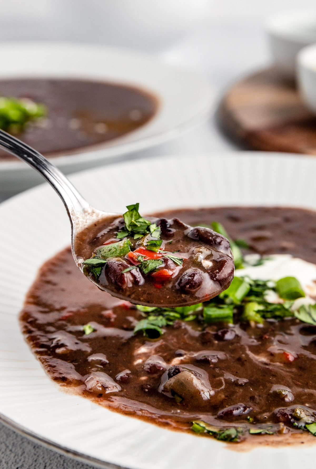 A spoonful is lifted from a bowl of black bean soup.