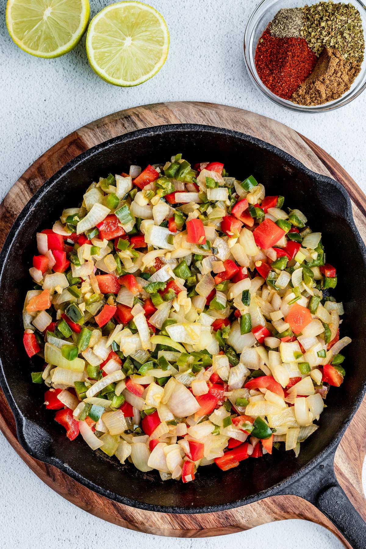 Veggies and herbs sautéing in a large skillet.