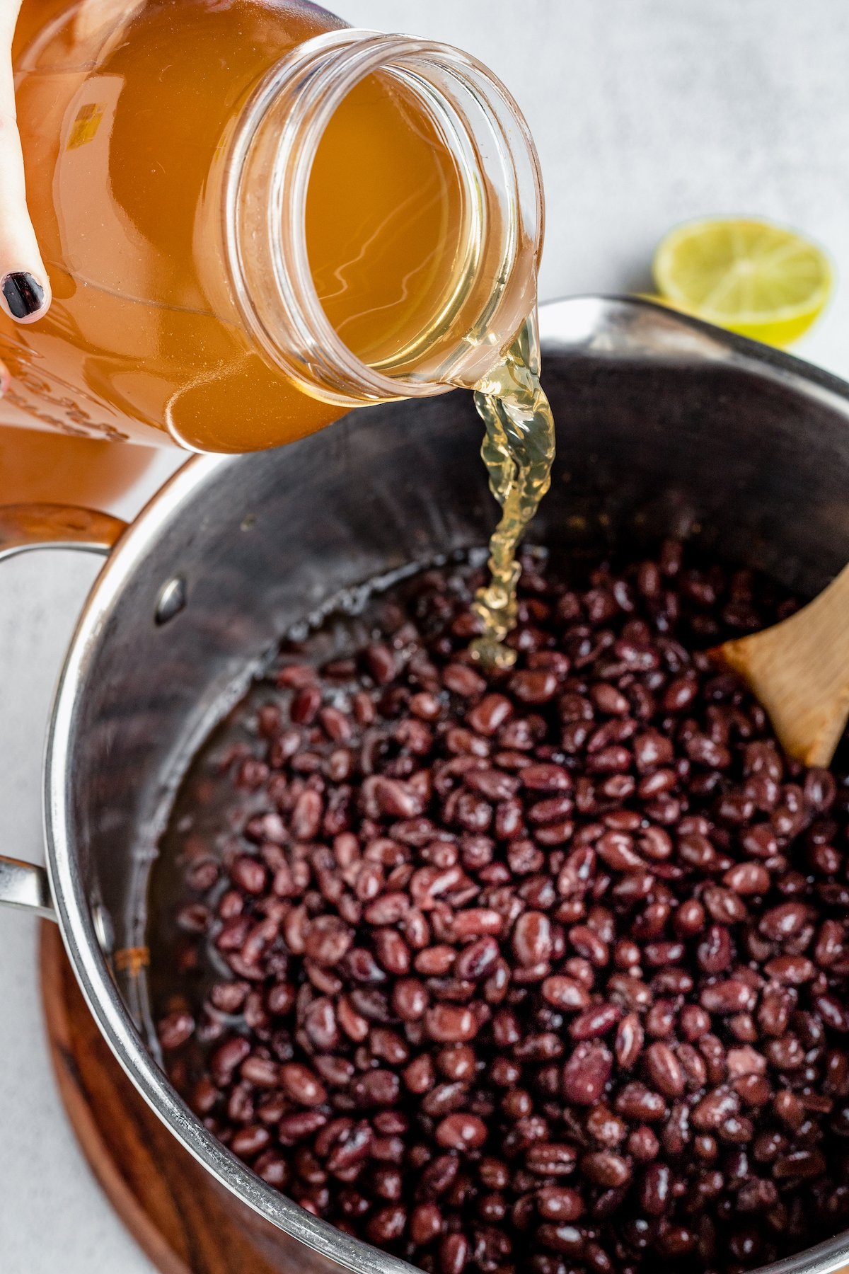 Black beans and broth are added into a pot with veggies.