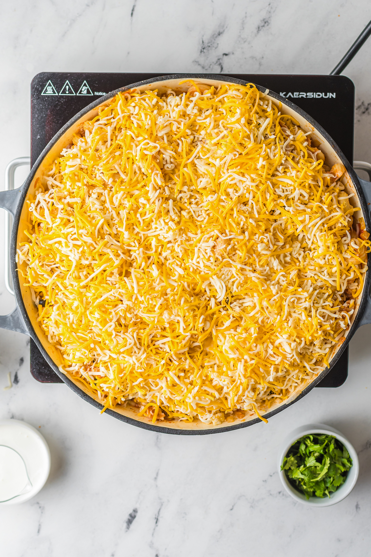 A round casserole dish with a layer of cheese sprinkled over the other ingredients inside.