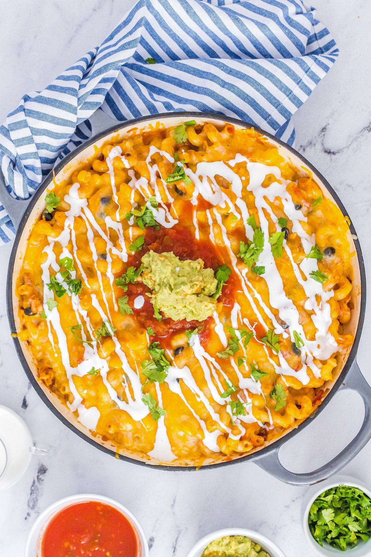 Overhead shot of a round baking dish filled with a cheesy casserole mixture topped with salsa and other toppings.