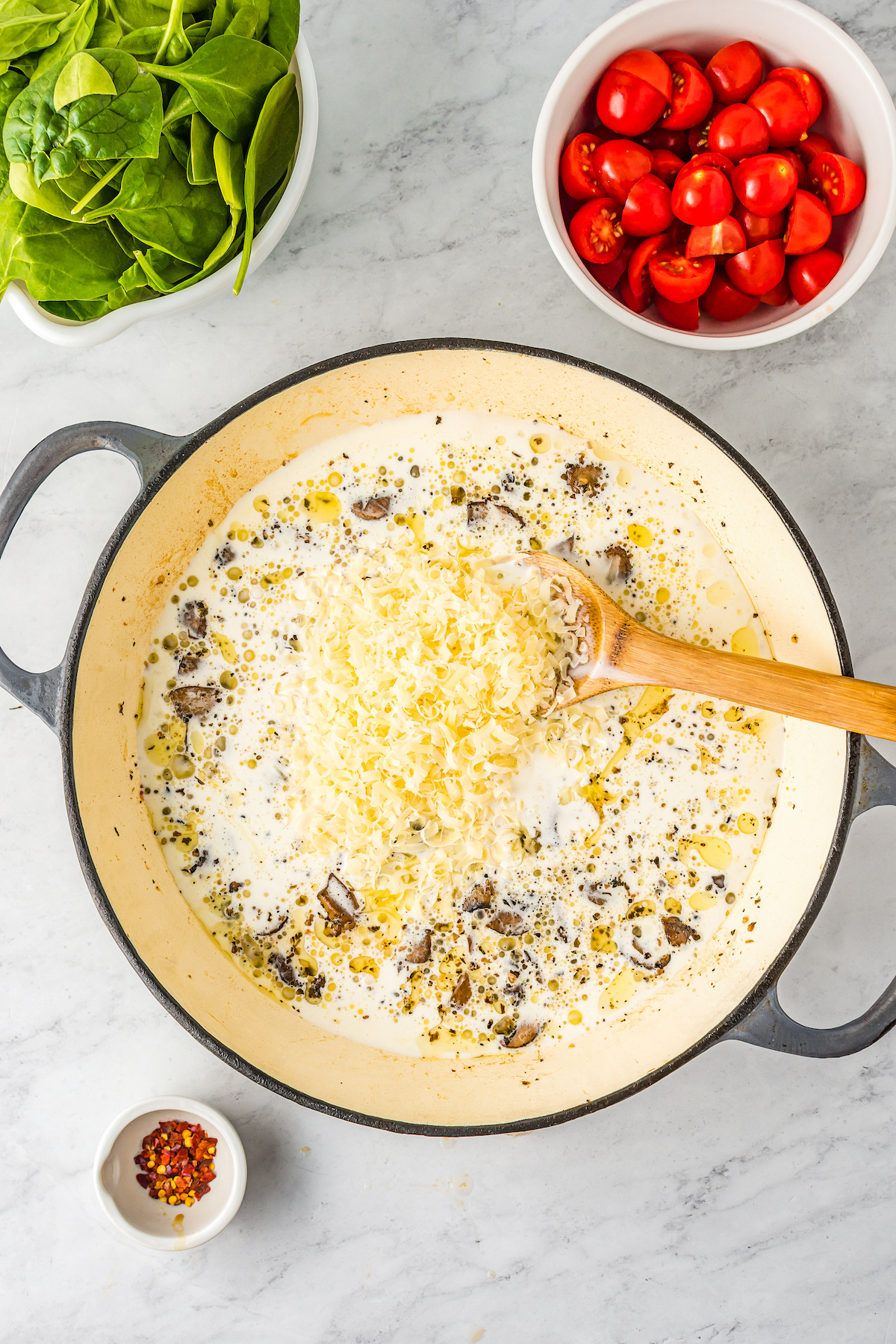 A skillet with cream, mushrooms, and cheese in it.