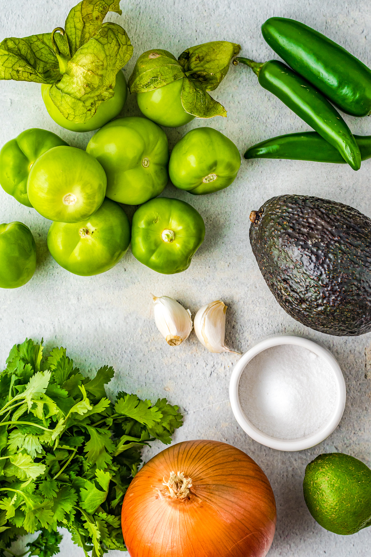 From top left: Fresh tomatillos, jalapenos, cilantro, garlic, avocado, salt, onion, lime.