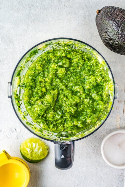 Overhead shot of a food processor with green salsa inside.