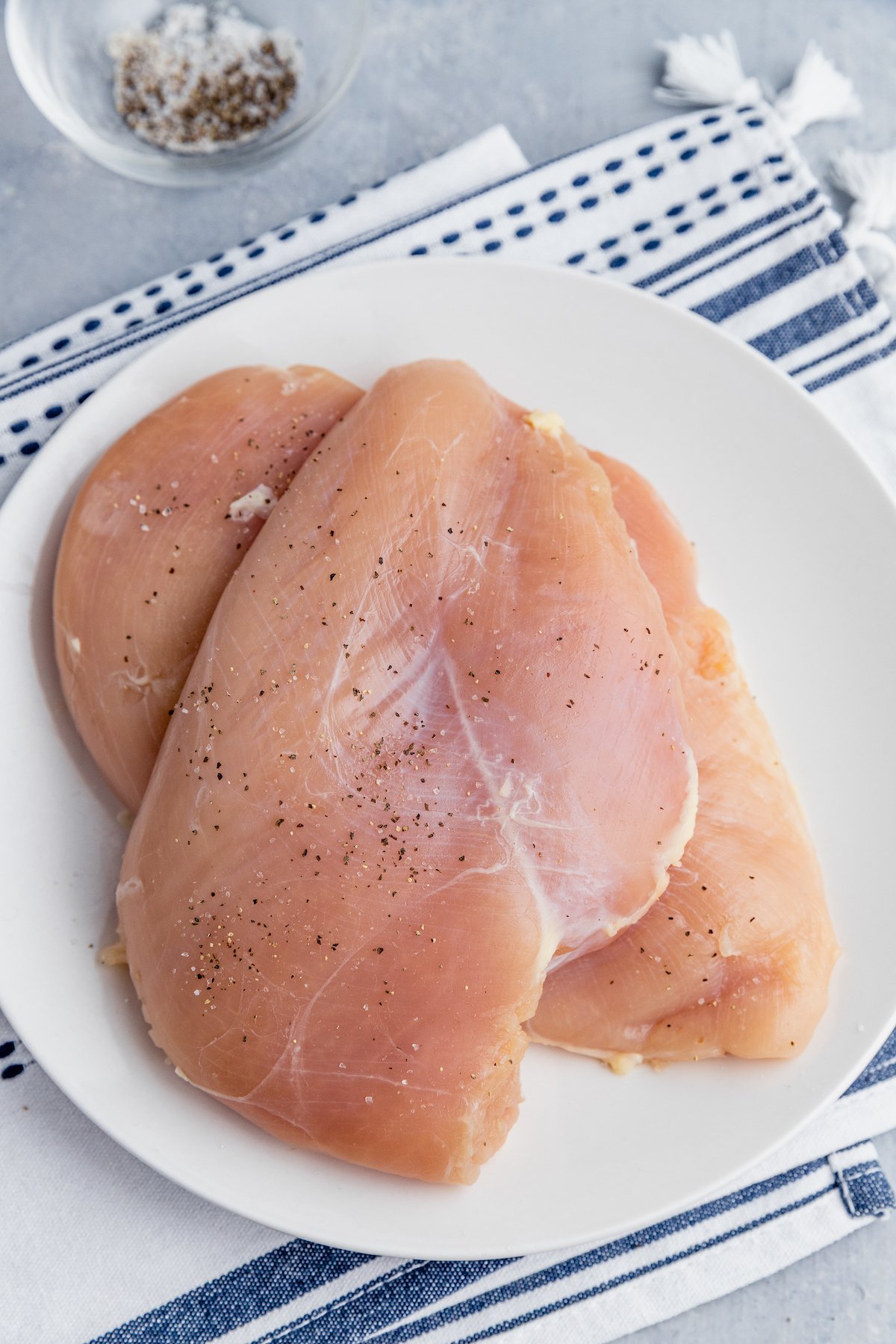 Two chicken breasts stacked on a white plate.