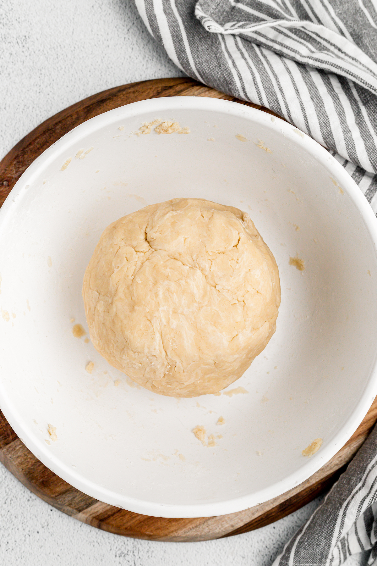 A ball of pie dough in a large white bowl.