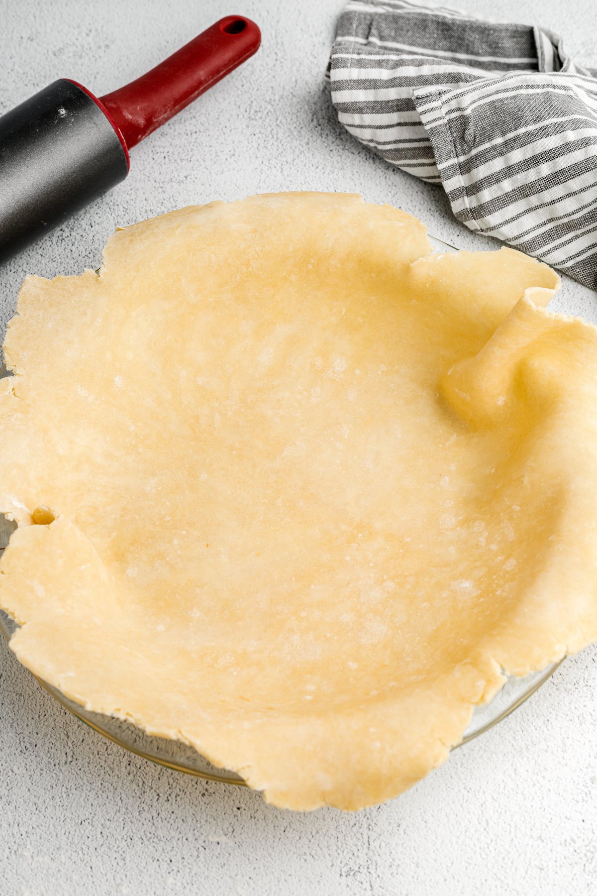 A sheet of pie dough is placed over a pie tin.