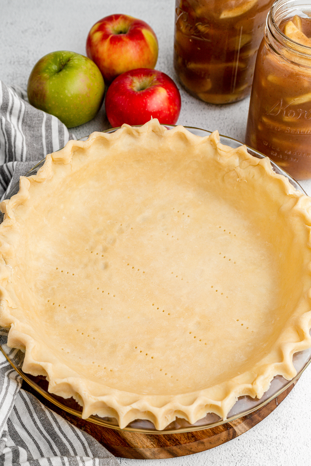 Top view of pie dough inside a pie tin, next to apples and pie filling.