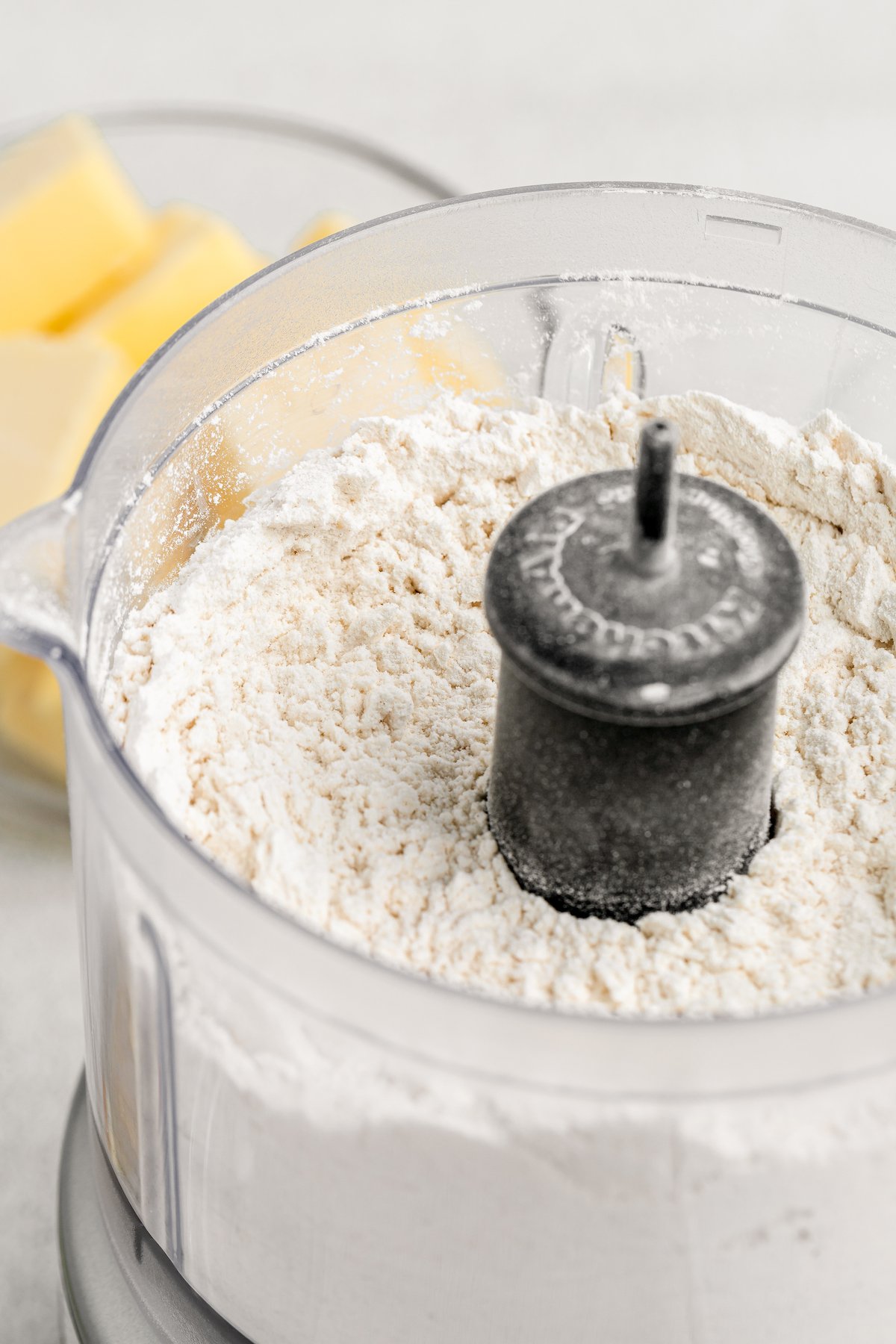 Flour and dry ingredients are added to a food processor.