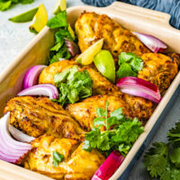 Tandoori chicken garnished with cilantro and red onion.