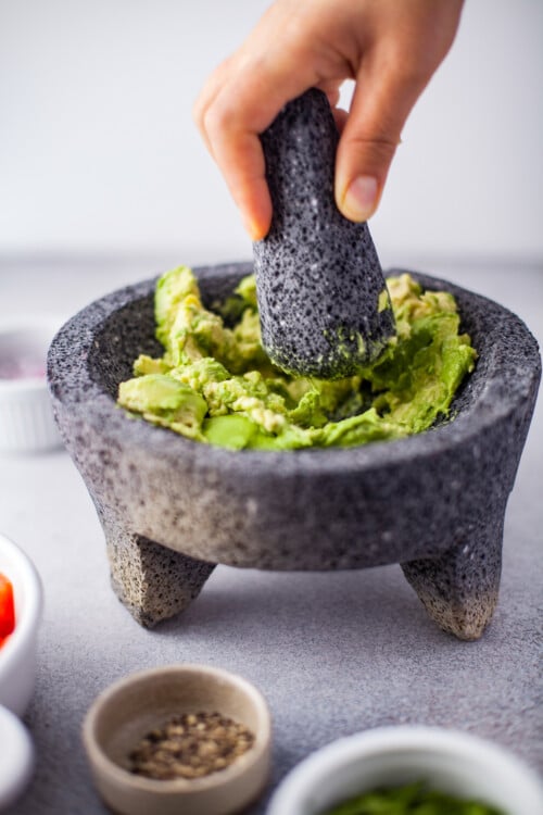 Mashed avocados in a mortar and pestle.