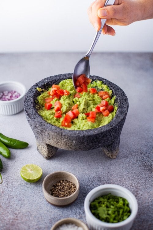 Avocados, tomatoes, onions, and other ingredients in a molcajete.