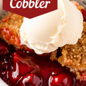 Up close image of cherry cobbler in a. bowl with ice cream on top.