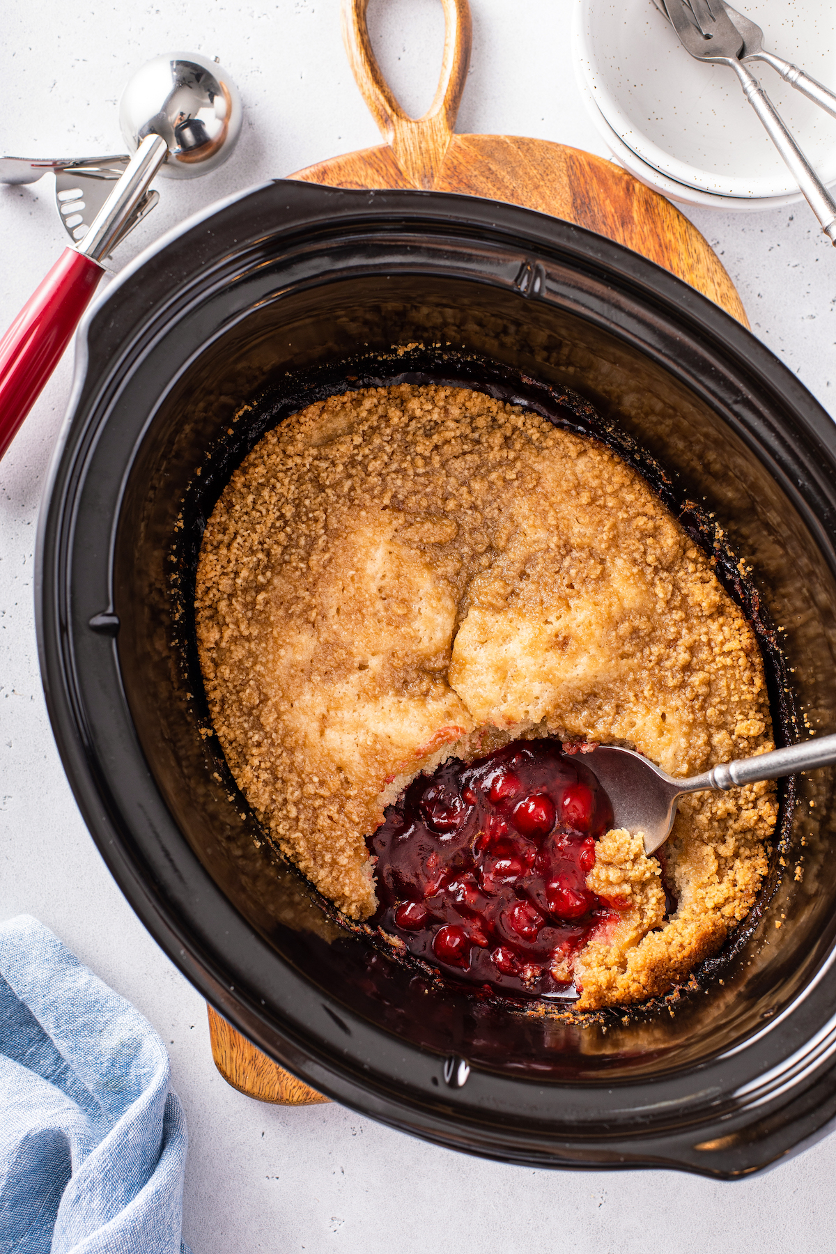 Cherry crockpot cobbler with a spoon scooping up a serving.