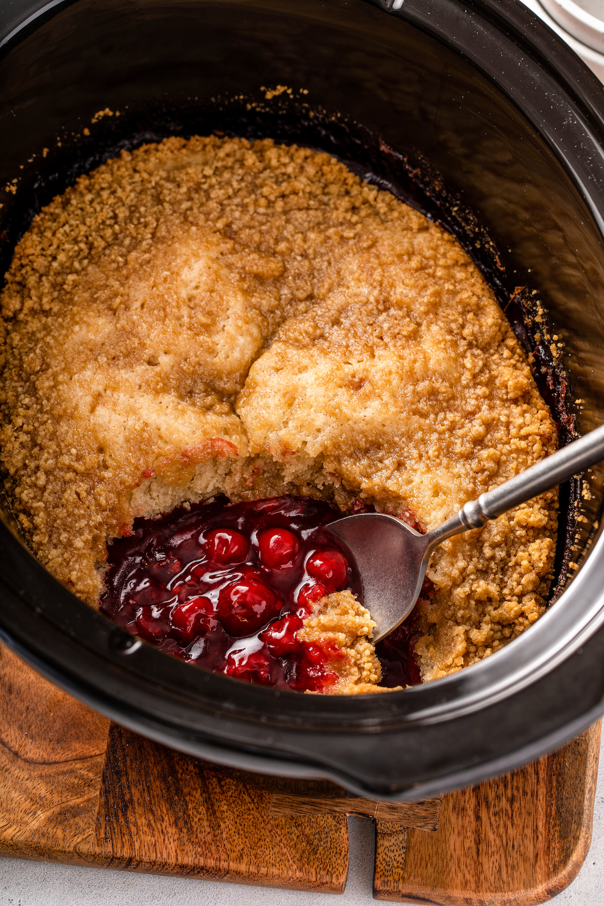 Cooked cobbler in crockpot with a spoon.