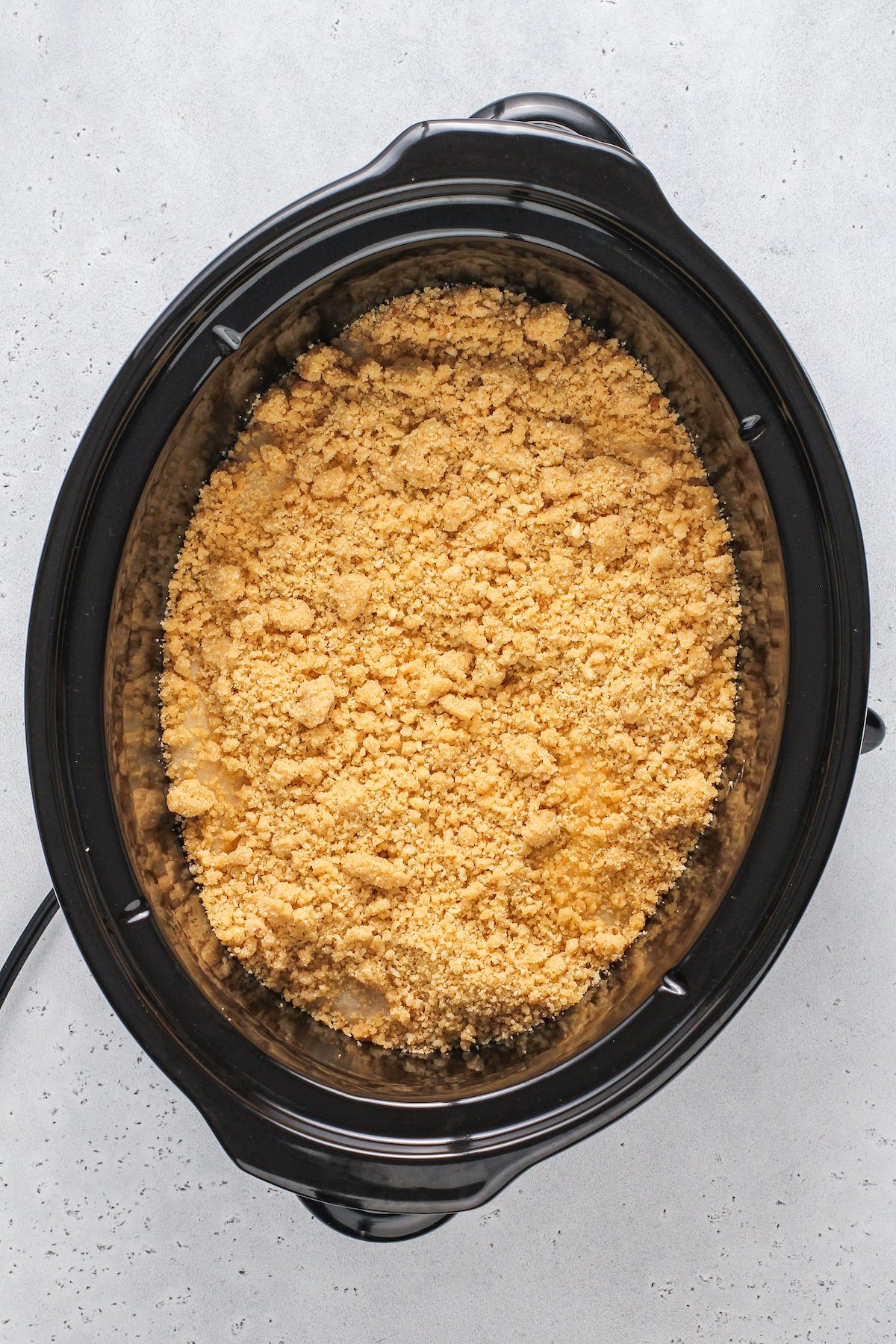 Crockpot filled with cobbler and brown sugar crumble topping.