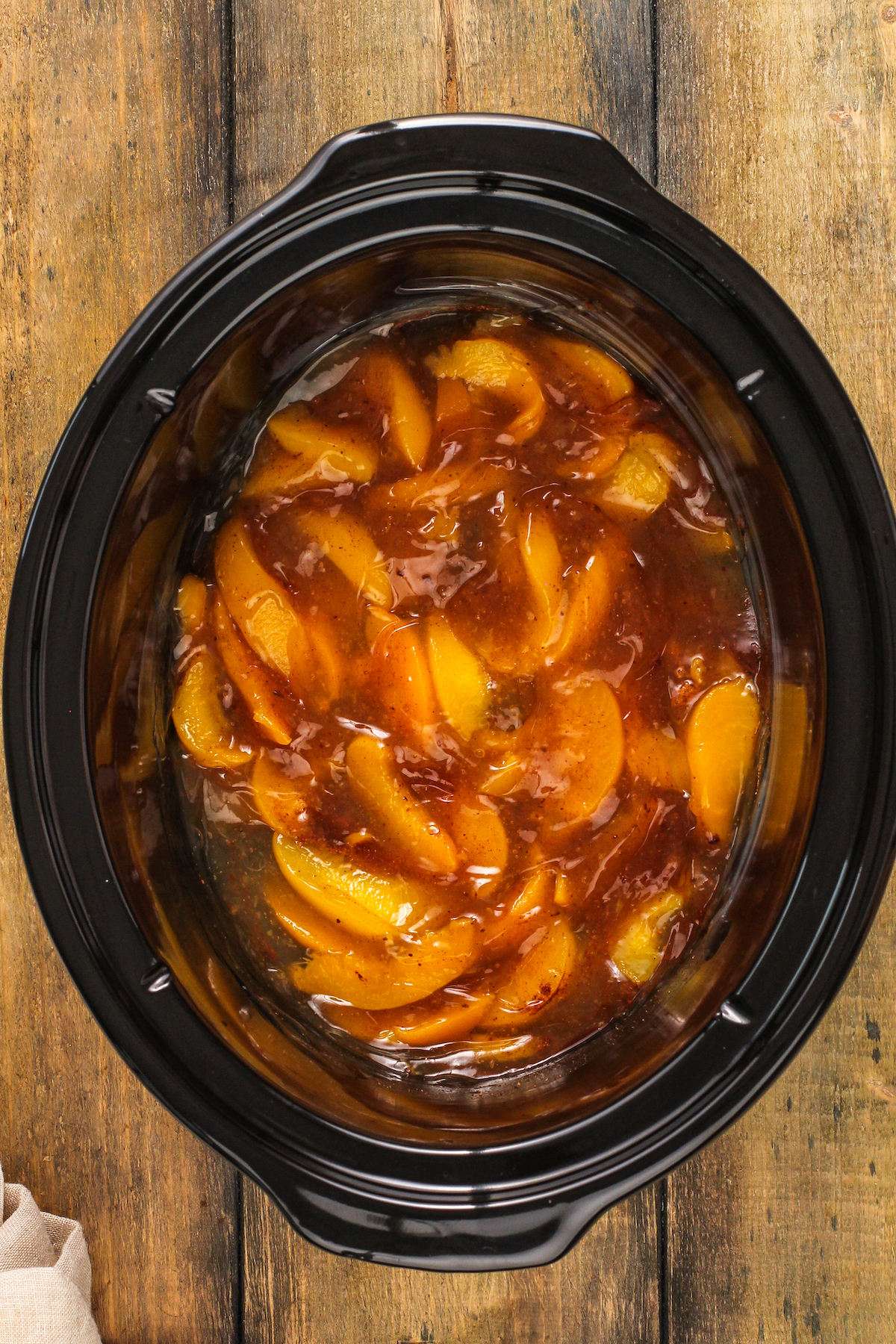 Peach filling mixture inside the bowl of a crock pot.