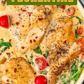 Chicken breasts in a creamy sauce with cherry tomatoes and spinach in a skillet.