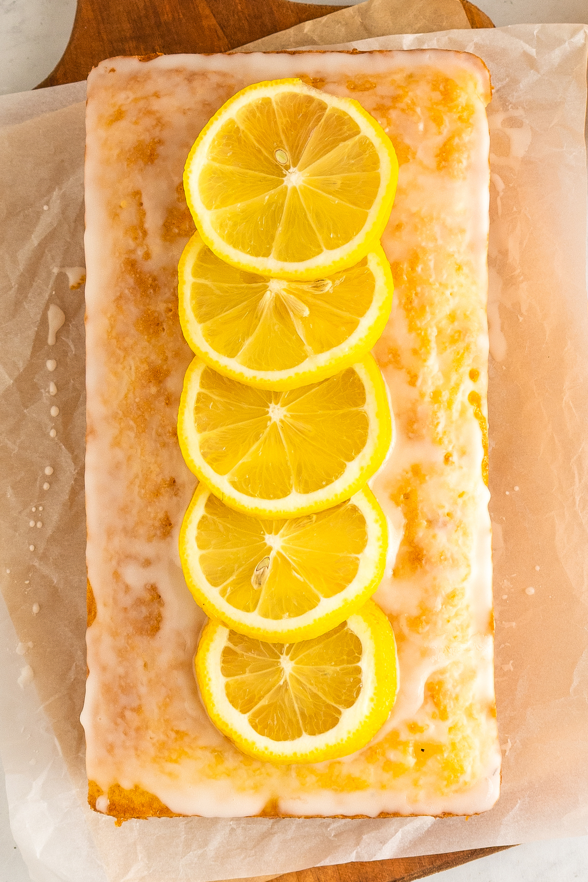 Overhead shot of glazed lemon bread, topped with slices of fresh lemon.