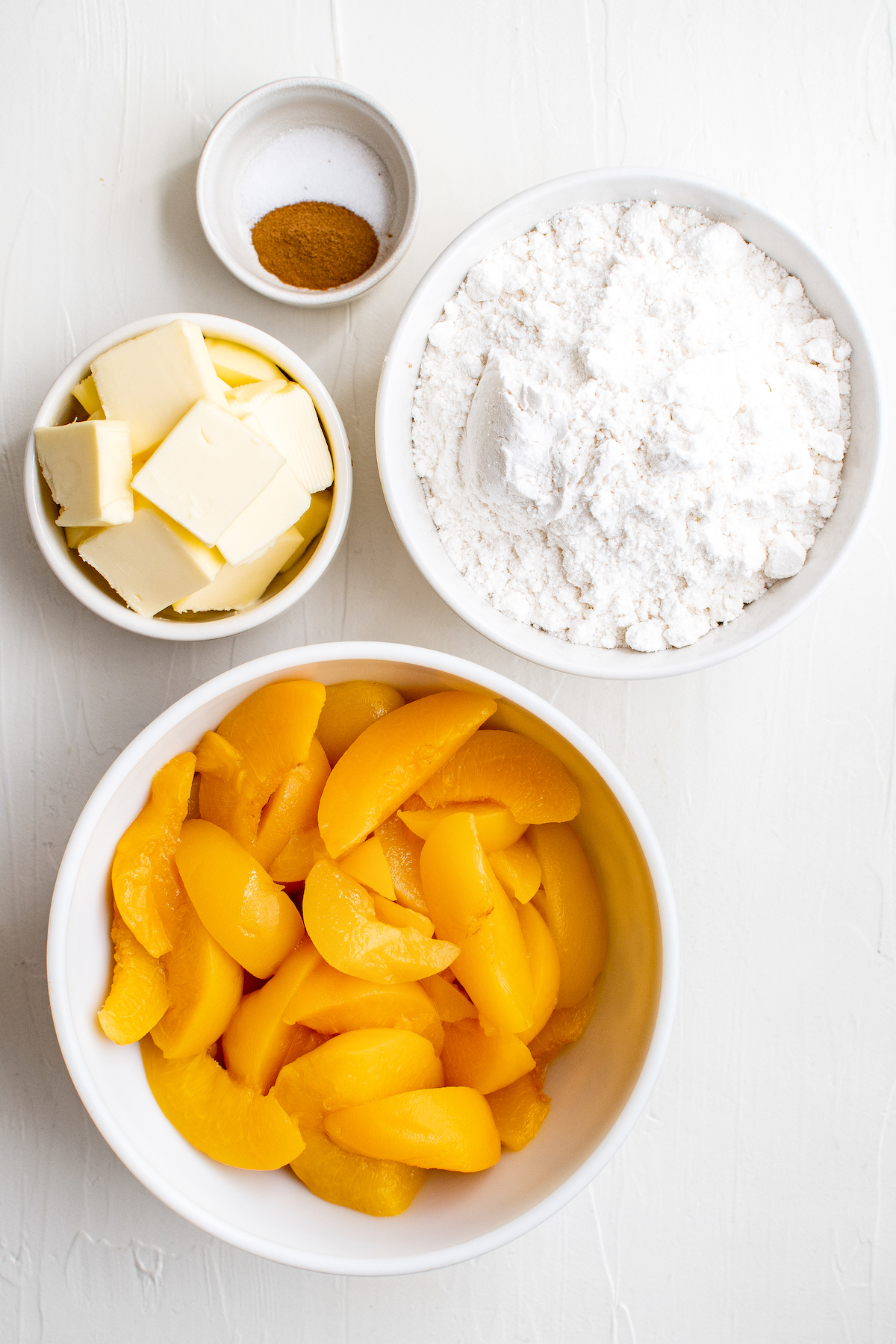 From top: Cinnamon, white cake mix, canned sliced peaches, butter.