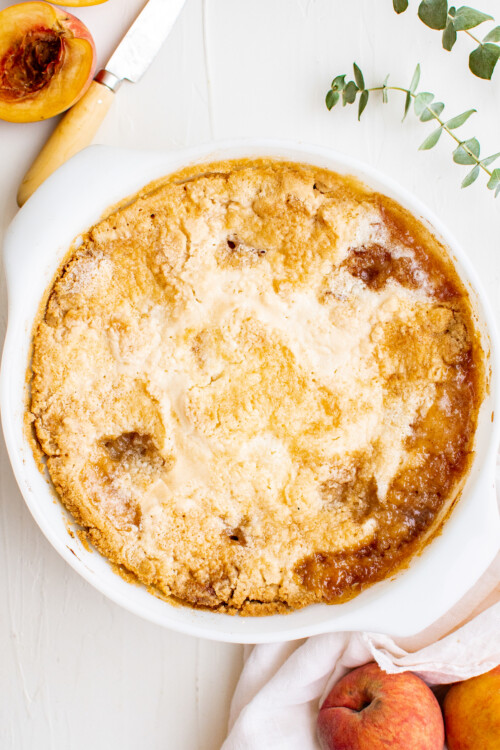 A baked peach dump cake, with a golden-brown topping and fruit filling.