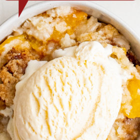 Up close image of peach dump cake in a white bowl with ice cream on top.