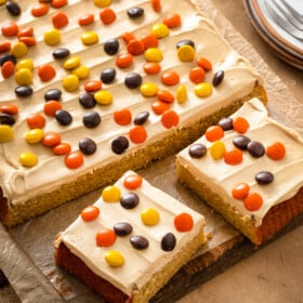 A frosted sheet cake sprinkled with Reese's Pieces and cut into generous squares.