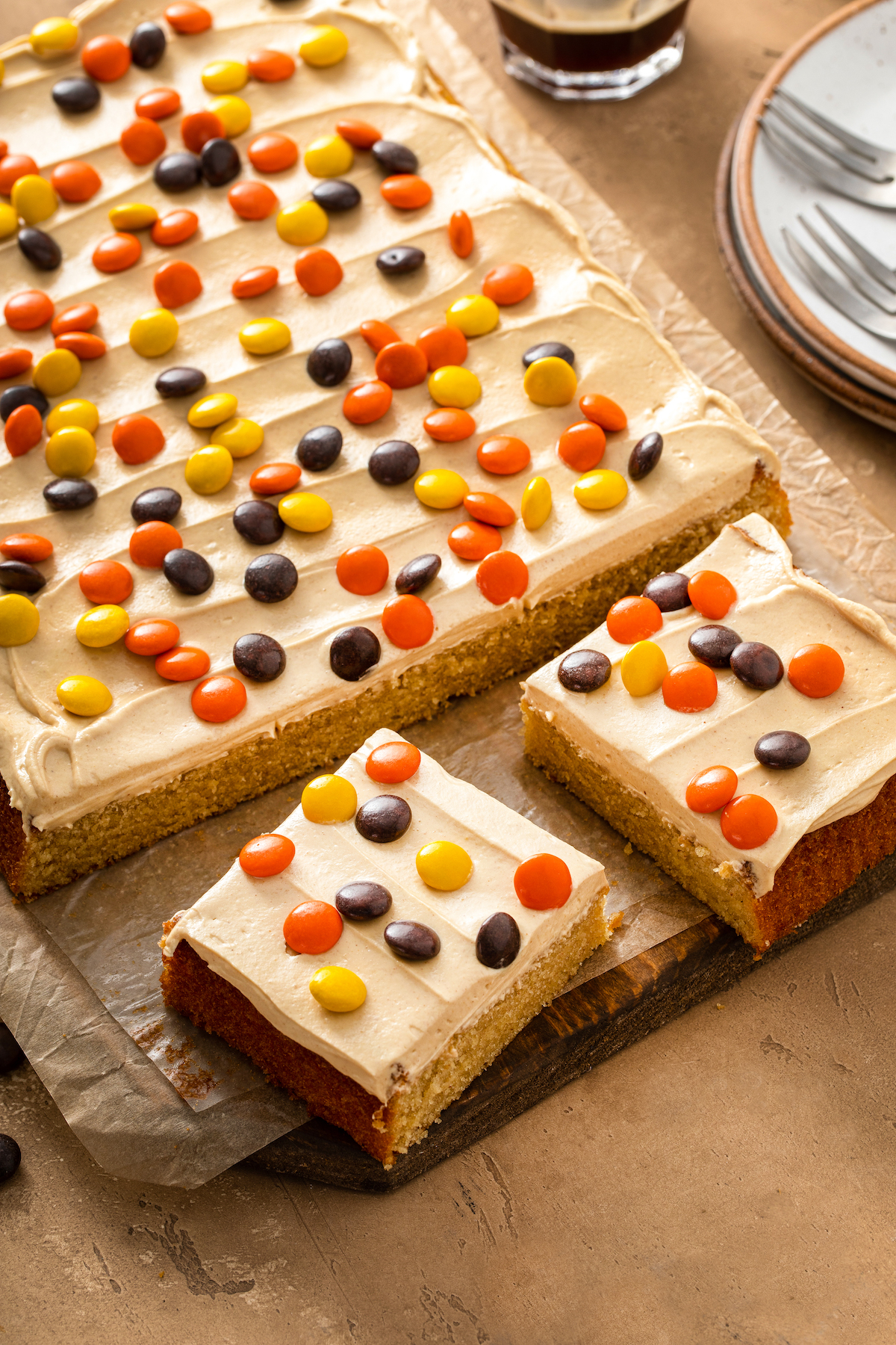 A frosted sheet cake sprinkled with Reese's Pieces and cut into generous squares.