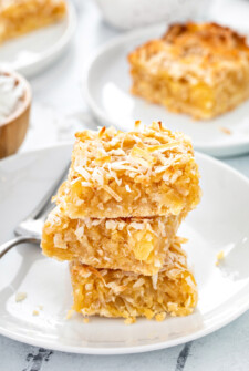 Close-up shot of pineapple coconut bars, stacked on a plate with a fork.