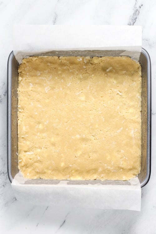 Unbaked shortbread in a square baking dish.